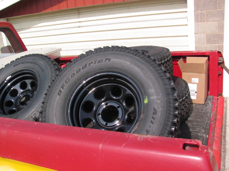 Spare BFGoodrich All-Terrain tires on black rims in red truck bed