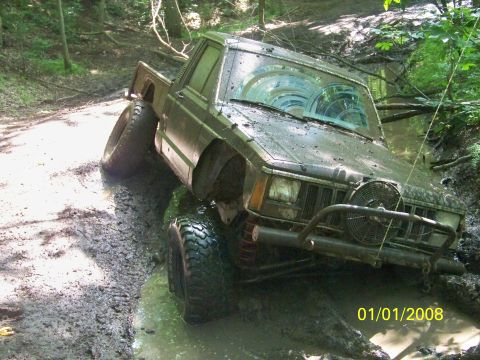 1989 Ford Bronco - This Jeep Cherokee XJ pickup truck is stuck in a muddy trail, with its front tires deep in the mire.