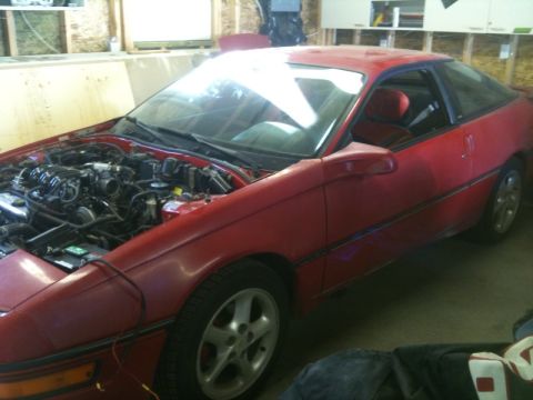 1990 Ford Probe - A red 1990 Ford Probe is parked inside a garage with its hood open, revealing the engine compartment.