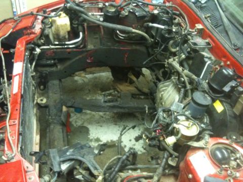 1990 Ford Probe - The engine bay of a red car is shown with the engine removed, revealing the internal components and wiring.