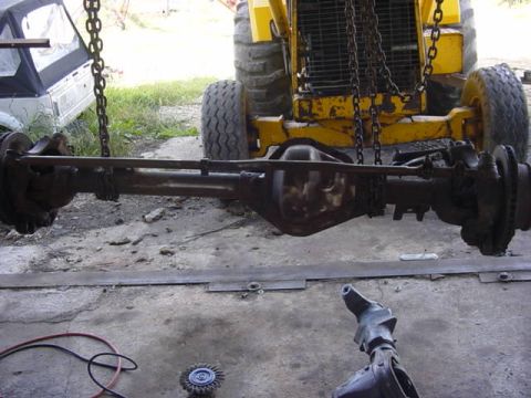 1992 Ford Bronco - A differential and axle assembly is suspended by chains, with a yellow loader visible behind it.