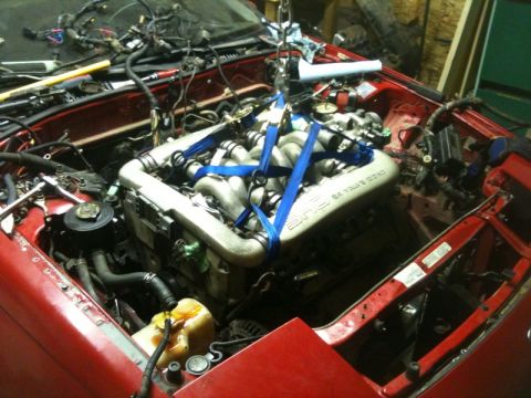 1990 Ford Probe - Engine removal in progress from a red vehicle, with the engine suspended by blue straps.
