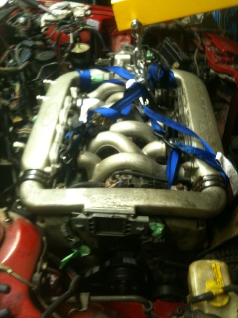 1990 Ford Probe - Engine bay detail with engine being hoisted out of the vehicle.