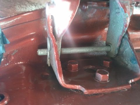1978 Ford Bronco - Close-up of a red painted metal door hinge mounting bracket with bolts visible.