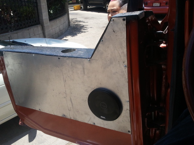 Custom door panel with a speaker and cup holder installed. A person is visible in the background