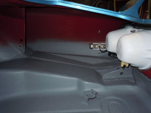 1972 Chevrolet Camaro - The interior of a car's trunk shows gray primer on the floor and red paint on the side panel, with two white tanks visible.