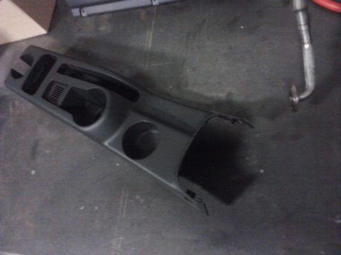 2001 Volkswagen Jetta - A black plastic center console part with two cup holders and a vent is shown from an overhead angle.