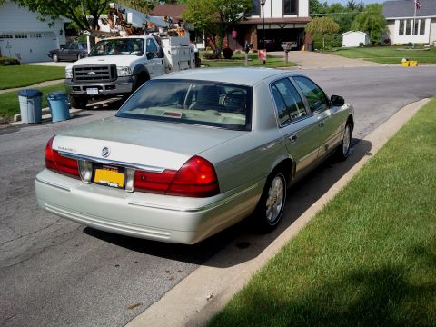 2004 Mercury Grand Marquis - Silver 2004 Mercury Grand Marquis seen from the rear, parked on a residential street with a utility truck in the background.