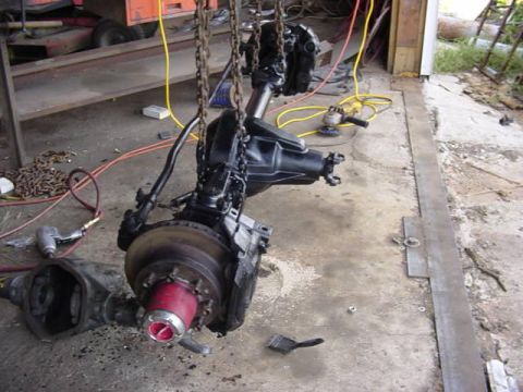 1992 Ford Bronco - Front axle assembly being worked on in a garage setting with tools nearby.