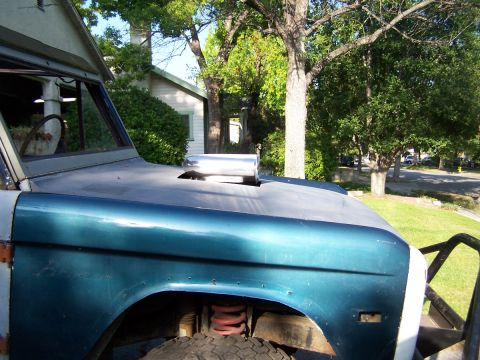 1973 Ford Bronco - A custom hood scoop protrudes from the hood of a classic Ford Bronco parked outdoors.