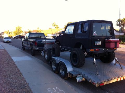 1987 Suzuki Samurai - A lifted Suzuki Samurai is loaded onto a trailer, ready for transport.