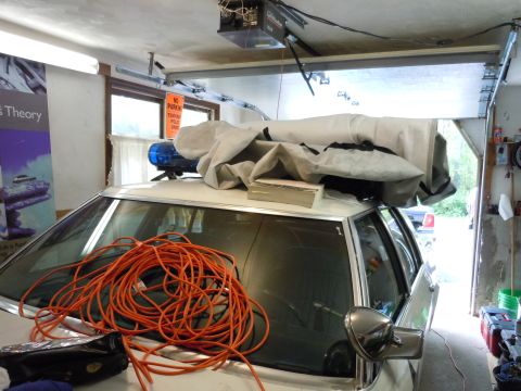 2001 Ford Crown Victoria - A white vehicle with emergency lights on the roof is parked inside a garage, partially covered.