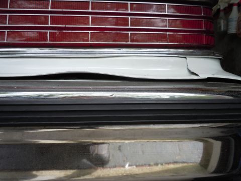 2001 Ford Crown Victoria - Close-up of a vehicle's rear bumper and taillight assembly, showing chrome accents and a damaged white body panel.