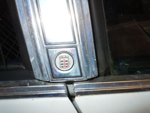2001 Ford Crown Victoria - Close-up of chrome trim and emblem on a white vehicle.