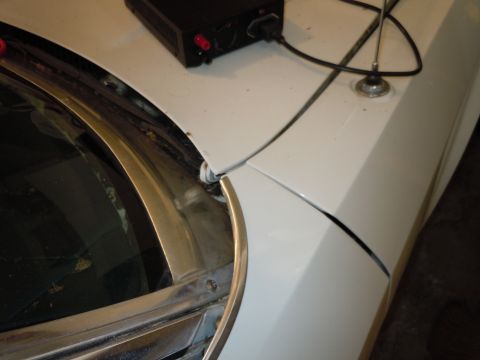 2001 Ford Crown Victoria - Close-up view of the hood and fender area of a white vehicle, showing an antenna and a black power supply unit.