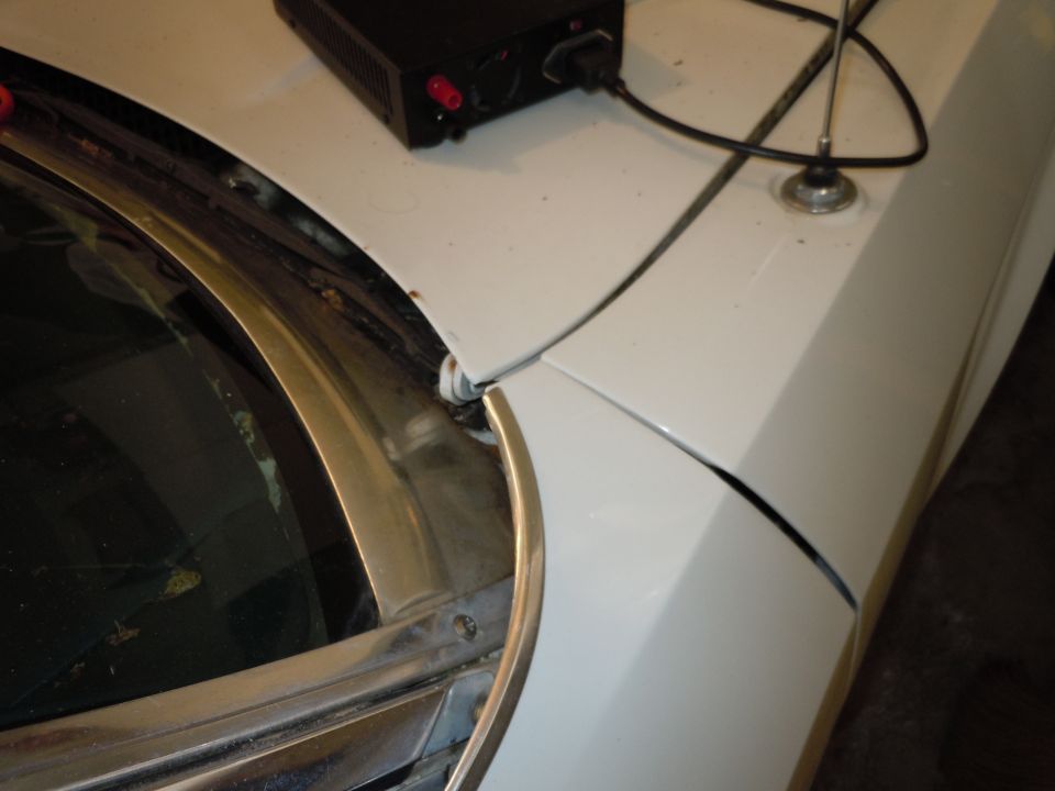 White car hood and fender detail with antenna and power supply