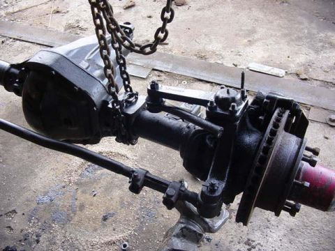 1992 Ford Bronco - Front axle assembly with disc brakes and steering linkage, suspended by chains.