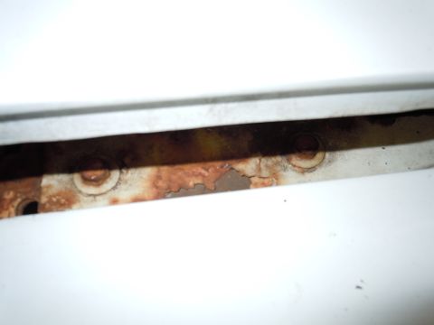2001 Ford Crown Victoria - This image shows a close-up view of a corroded metal strip, likely a component from a vehicle, with visible bolt heads.