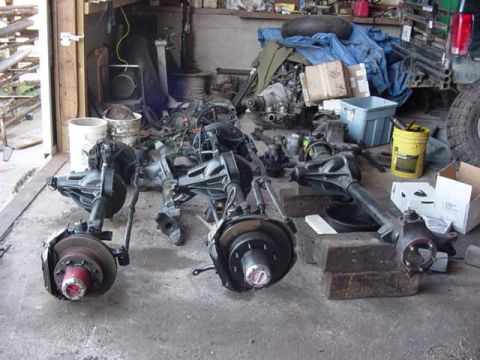1992 Ford Bronco - Vehicle axles and assorted parts are stored in a workshop setting.