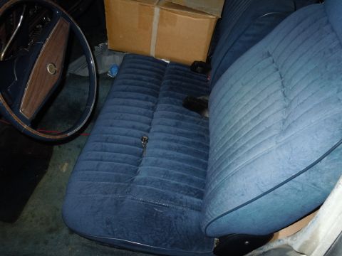 2001 Ford Crown Victoria - The interior of a car shows a blue velour bench seat and a wooden-accented steering wheel.