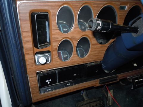 2001 Ford Crown Victoria - Close-up of a car's interior dashboard, wood-grain accents and multiple control buttons and gauges.
