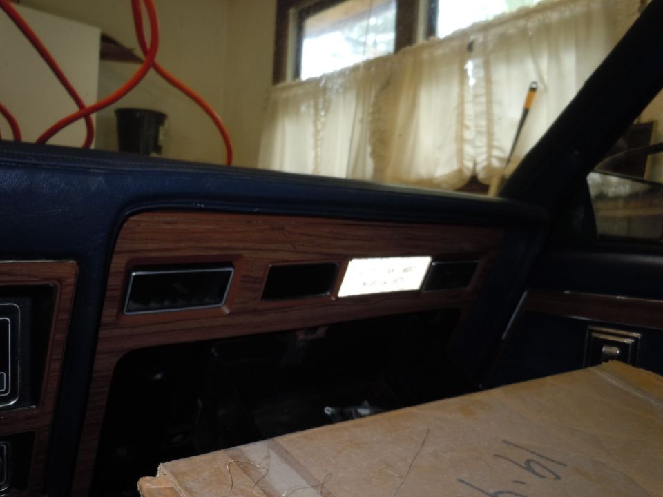 Car interior dashboard with wood grain trim and a lit panel showing some text