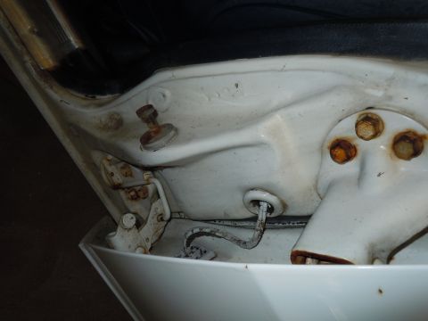 2001 Ford Crown Victoria - Close-up view of a white door hinge mechanism showing signs of rust and wear.
