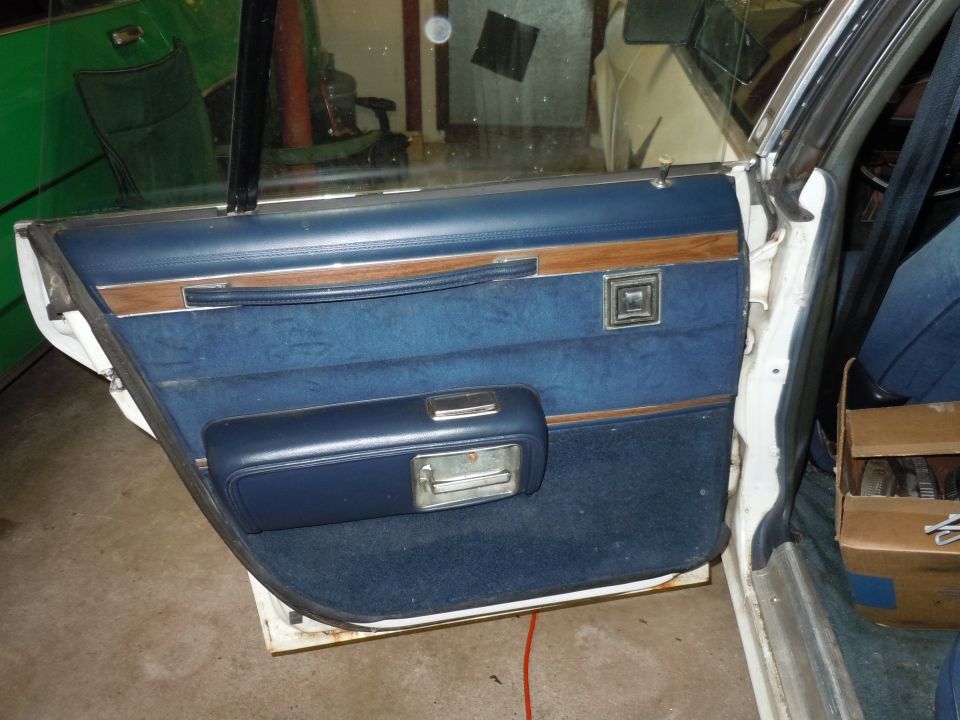 Interior door panel with blue carpet and vinyl, wood trim, and chrome door handle