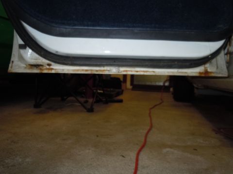 2001 Ford Crown Victoria - The lower door sill of a white vehicle shows significant rust and a black rubber seal.