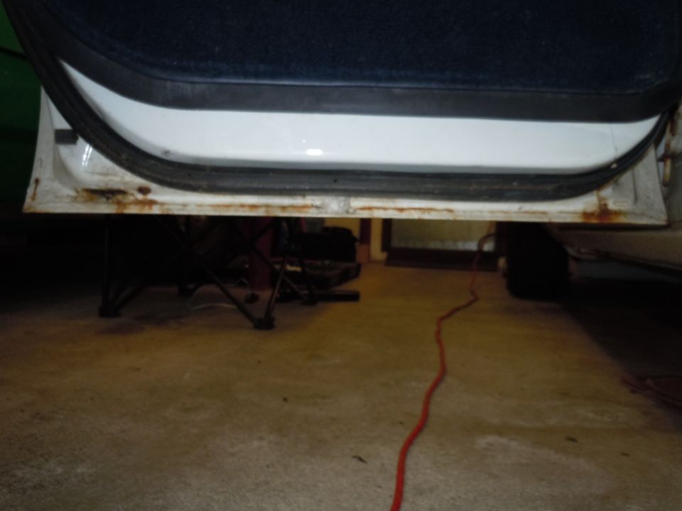 White car door sill with visible rust and a black rubber seal
