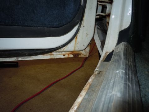2001 Ford Crown Victoria - Interior view of a vehicle's door frame and sill, showing rust and a red wire on the floor.