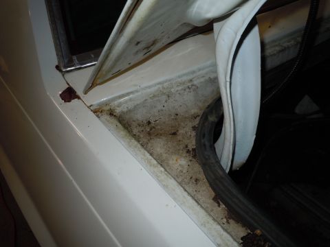 2001 Ford Crown Victoria - Close-up of a car's door jamb reveals rust and debris, indicating potential wear and tear.