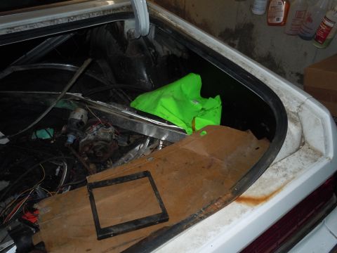 2001 Ford Crown Victoria - Contents of a car trunk, including engine parts and a neon green tarp, are visible.