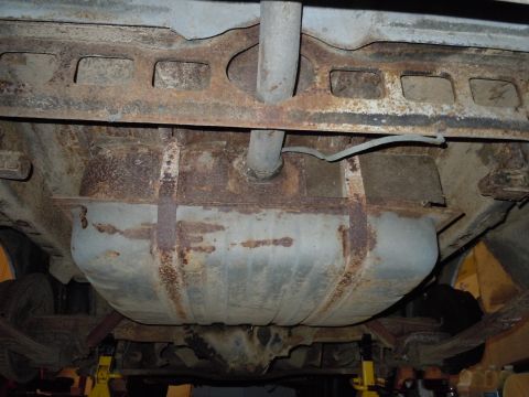 2001 Ford Crown Victoria - The heavily rusted undercarriage of a vehicle is visible, with a large fuel tank and exhaust system.