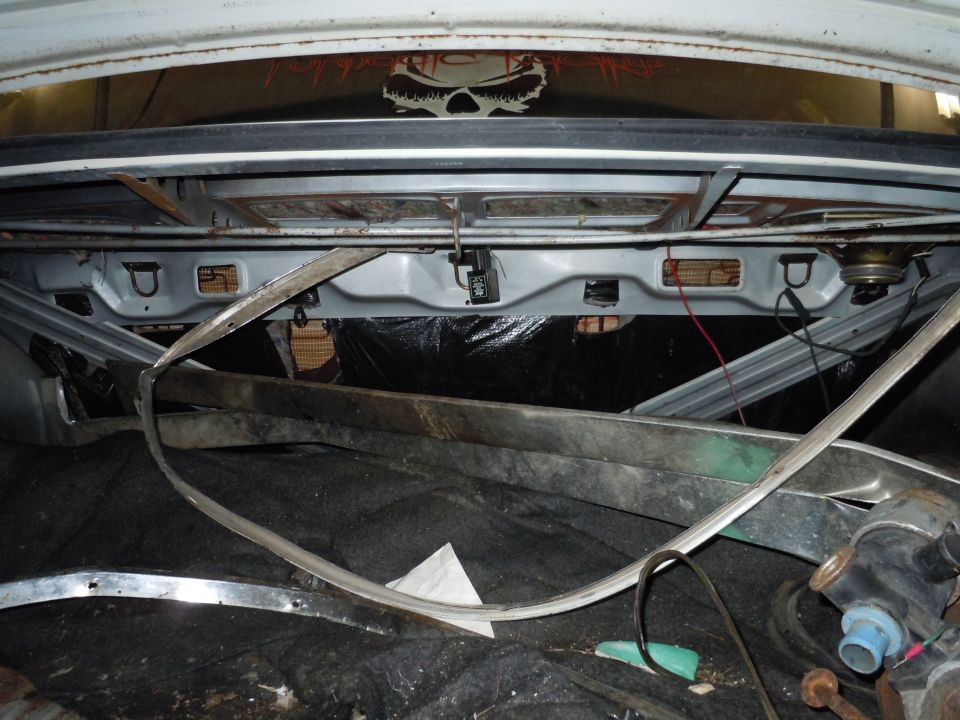 Interior of a car trunk, showing exposed metal and debris