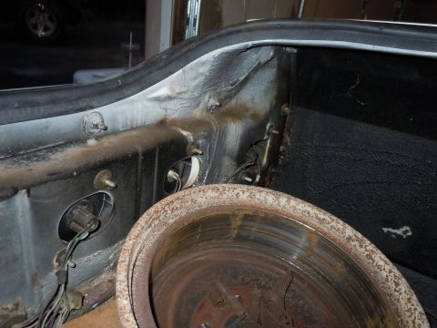 2001 Ford Crown Victoria - Rusty brake rotor and interior trunk structure with visible wiring and mounting points.