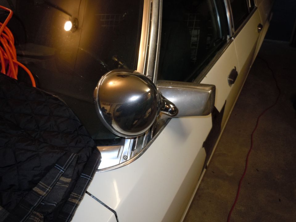 Chrome side mirror assembly and part of door on white vehicle