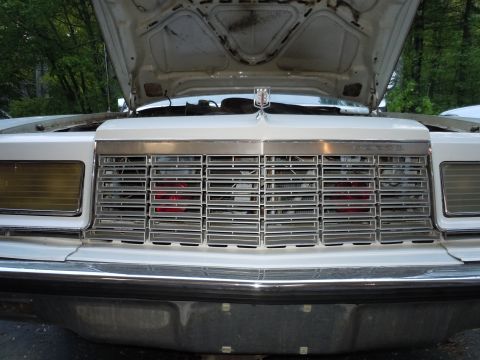 2001 Ford Crown Victoria - Front view of a white vehicle with its hood open, revealing a chrome grille and amber turn signals.