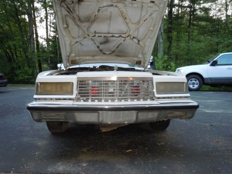 2001 Ford Crown Victoria - Front view of a 1983 Chrysler New Yorker, hood up, with a white SUV in the background.