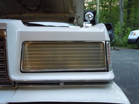 2001 Ford Crown Victoria - Close-up of a white sedan's front grille and headlight area, with the hood raised.