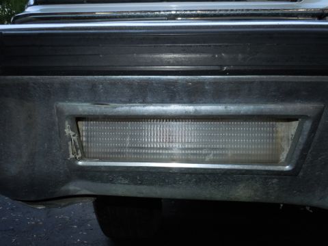 2001 Ford Crown Victoria - Close-up of a 2001 Ford Crown Victoria's rear bumper reflector, revealing wear and tear.