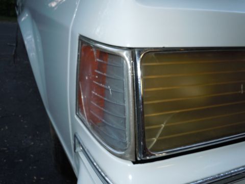 2001 Ford Crown Victoria - Close-up of a white vehicle's rear corner, showing the taillight assembly with amber and clear sections and chrome accents.