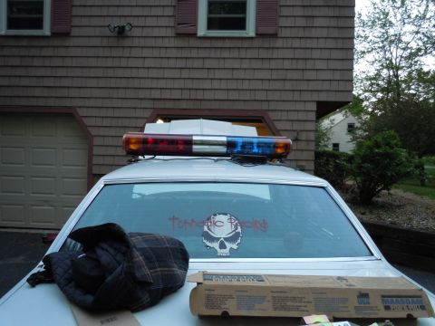 2001 Ford Crown Victoria - The vehicle has a light bar and a skull sticker on the rear window, suggesting it may be modified.
