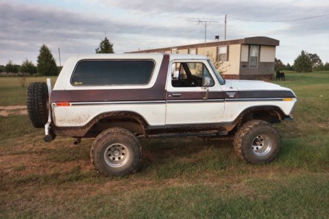 1978 Ford Bronco - This lifted Ford Bronco is parked outside a trailer home on a cloudy day.