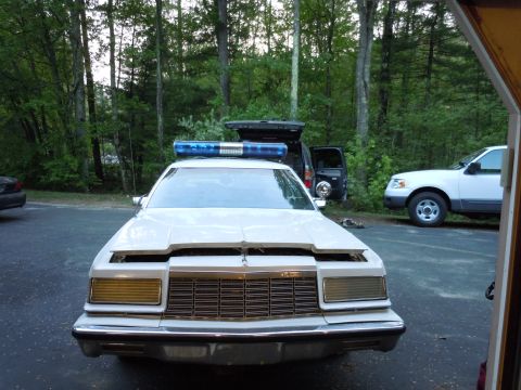 2001 Ford Crown Victoria - Front view of a white police car with an open hood and a light bar on the roof.