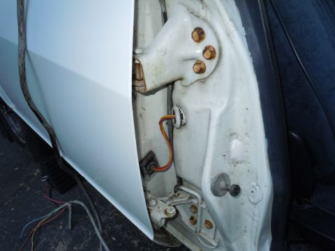2001 Ford Crown Victoria - The interior of a car door jamb, revealing the hinge and electrical wiring. The body is painted white.