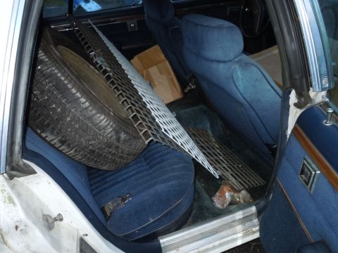 2001 Ford Crown Victoria - The interior of a car is filled with a spare tire and a metal grate, obscuring the view of the seats and floor.