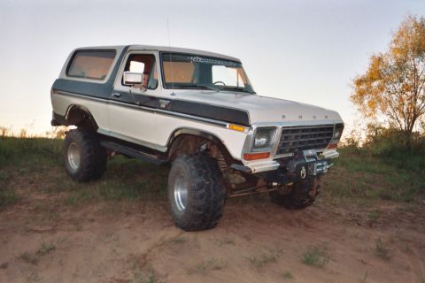 1978 Ford Bronco - A lifted 1978 Ford Bronco with a winch is parked on a grassy hill under a clear sky.