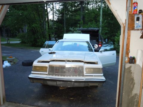 2001 Ford Crown Victoria - A white sedan sits in a garage with its hood and doors open, revealing its front end.
