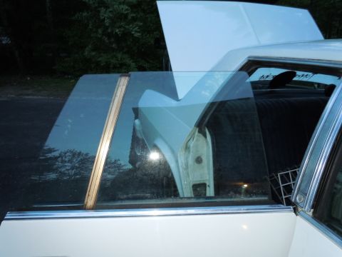 2001 Ford Crown Victoria - Side view of a white sedan with its hood open and driver's door ajar, revealing the interior and a glimpse of text on the rear window.